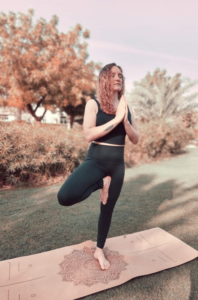 Alina Saibel, yoga instructor, standing in Tree Pose (Vrikshasana) with eyes closed during an outdoor yoga session – a moment of focus, balance, and calm